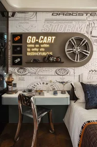 Cozy bedroom with a bed, chair, desk, and motorcycle, featuring various items on the desk and a warm atmosphere