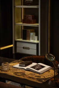 A well-organized bookshelf with a wooden bookcase, books, a cup, a vase, and a clock, creating a cozy and inviting living space atmosphere