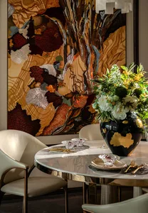 Dining area with a round table, two chairs, wine glasses, and a vase with flowers, set in a sophisticated and inviting atmosphere
