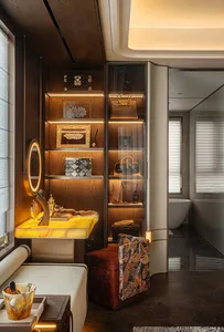 Modern bathroom with beige walls, a white toilet, sink, and bathtub, and a brown wooden cabinet, with dim lighting creating a cozy atmosphere