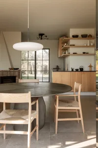 Warm and inviting kitchen and dining space with wooden floors and cabinets, featuring a dining table and chairs, and decorative bowls