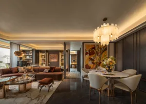 Elegant living room with a large couch, dining table, chairs, vases, and a potted plant, creating a sophisticated and inviting atmosphere