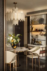 Dining area with a round table, chairs, a vase with flowers, and wine glasses, creating a luxurious and inviting atmosphere