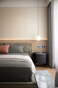 Cozy bedroom with a large bed, grey comforter, and wooden floor, set against a minimalist white backdrop