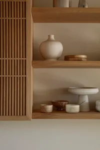 A wooden bookshelf with bowls, vases, and cups arranged on its shelves, showcasing a functional storage solution