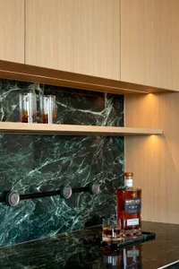 A kitchen with a marble countertop, whiskey bottle, and two wine glasses, creating an elegant and sophisticated atmosphere