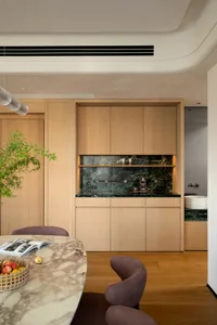 Warm kitchen space with wooden cabinets and countertops, featuring a dining table, chairs, and decorative bottles