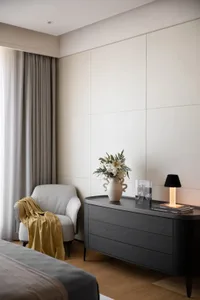 Cozy living room with a couch, two chairs, a table with a vase and book, and a remote control, set against a neutral background