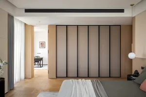Empty modern living area with hardwood floors, white walls, and large sliding doors leading to another room