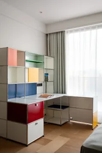 A modern office space with a desk, chair, bookshelves, and a bed, featuring a functional and minimalist design