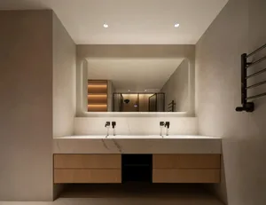 Bathroom with a large marble sink, two faucets, two mirrors, and a wooden cabinet, lit with bright and inviting lighting