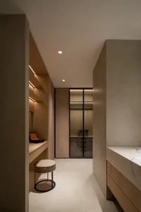 Bathroom with marble walls, a sink area, toilet, shower, and a chair for additional seating, creating a clean and well-organized space with a focus on functionality and aesthetics