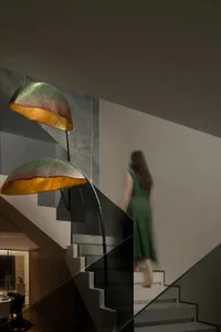 A woman in a green dress walks down a staircase with concrete steps, flanked by two lights