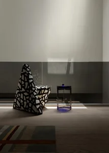Dimly lit living room with a black and white chair, two tables, and a cozy atmosphere