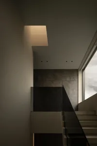 A dimly lit staircase with concrete steps and a window above, casting natural light into the space