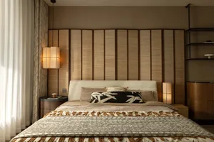 Cozy bedroom with a large white bed, brown headboard, wooden panels, and ample lighting from two lamps