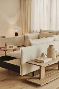 Cozy living space with a wooden floor, a couch, a chair, and decorative elements like vases and a book