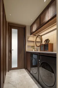 Small bathroom with two sinks, one with a mirror, and a potted plant near the center, featuring wooden doors and cabinets