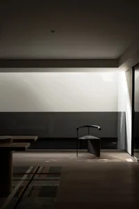 Empty modern room with a black chair in front of a glass wall, surrounded by white walls and a minimalist aesthetic