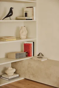 A bookshelf filled with books and decorative items, featuring vases and birds, creating a cozy and inviting atmosphere