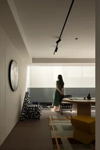 Modern dining space with a black and white theme, featuring a dining table and chairs, a clock on the wall, and a woman standing near the table