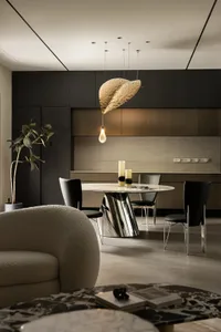 Elegant dining area with a round metallic table, chairs, a couch, and potted plants