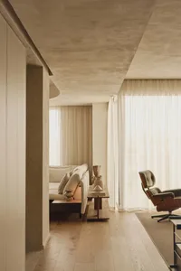 Cozy living area with a white couch, two chairs, a dining table, and a potted plant, with ample seating options for relaxation or socializing