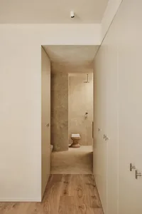 Bathroom with tile walls, a toilet, and two doors, creating a calm and inviting atmosphere