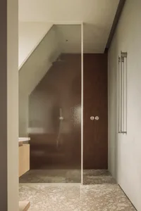 A well-lit bathroom with a glass shower door and brown wood trim, creating an inviting atmosphere