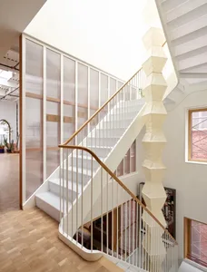 Modern staircase with wooden steps and white railing, surrounded by natural light from two windows on either side
