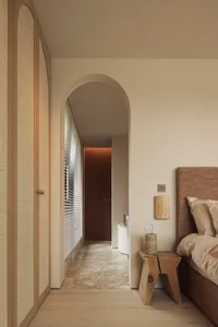 A calm and inviting bedroom with a large bed, white walls, wooden floors, and a few personal touches