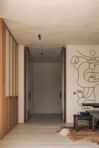 A clean and bright hallway with two doors, one on the left and another further down the hall, featuring white walls and no visible furniture or people