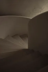 A curved wooden staircase with a railing in a bright, daytime setting