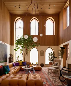 Modern living room with a large couch, chairs, dining table, potted plants, artwork, and clean lines