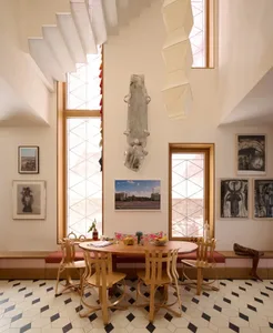 Cozy dining space with a wooden table, chairs, and various decorative items, lit by natural sunlight