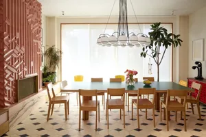 A dining area with a wooden table and chairs, surrounded by potted plants, creating a cozy atmosphere