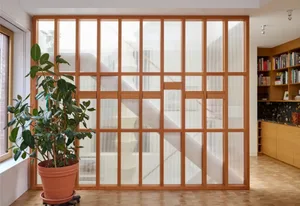 A well-lit home office with wooden blinds, two potted plants, and a calm atmosphere