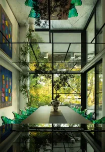 A modern dining area with a large glass table surrounded by multiple chairs, creating a sophisticated atmosphere