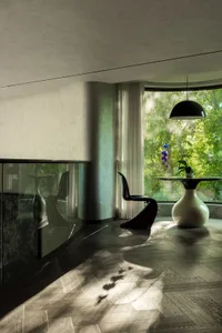 Dining area with a wooden table and chairs, natural light, and a potted plant
