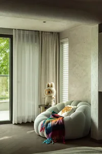 Cozy living space with a white ottoman, curtains, and a window