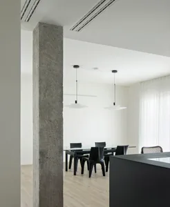 A modern dining space with a large table surrounded by chairs, featuring a white color scheme and a clean appearance