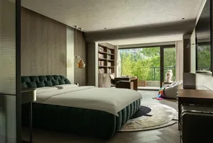 Cozy bedroom with a large bed, green headboard, books, and a chair, creating a relaxing atmosphere