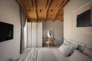 A cozy bedroom with a large bed, two chairs, a mirror, and wooden floors and possibly walls, creating a warm and inviting atmosphere