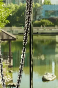 A serene indoor space with a large glass window overlooking a tranquil lake, featuring chains hanging in front of the window