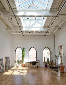 Open living area with a skylight, potted plants, chairs, and a desk, featuring a bright and inviting atmosphere with a focus on functionality and comfort
