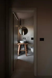 Bathroom with a wooden sink stand, mirror, and toilet, featuring a simple and functional design