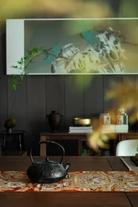A warm and inviting dining space with a wooden table, chairs, vases, potted plants, and a teapot, set in a well-lit room