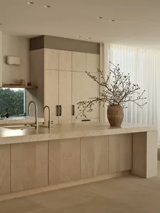A clean and well-organized kitchen with white cabinets and countertops, a vase with flowers, and two potted plants, creating a bright and inviting atmosphere