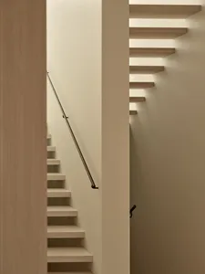 A narrow stairwell with wooden steps and a white color scheme, set against a blank background