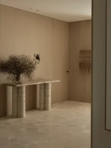 Empty room with wooden walls and floors, featuring two vases on a table in the center, creating a calm and minimalistic atmosphere